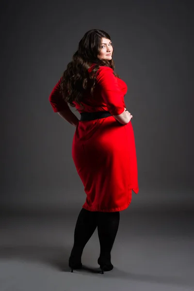 Plus-Size-Modell im roten Kleid, dicke Frau auf grauem Hintergrund, übergewichtiger weiblicher Körper — Stockfoto