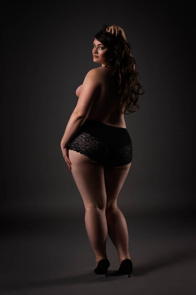 Plus size sexy model in underwear, fat woman on gray studio background, overweight female body, full length portrait, rear view