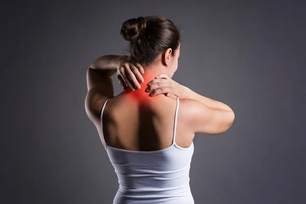 Боль в шее, женщина с болью в спине на сером фоне — стоковое фото