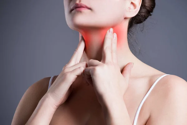 Болить горло, жінка з болем в шиї, сірий фон — стокове фото