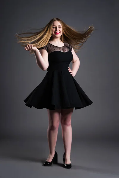 Счастливая модель plus size в черном платье, толстая женщина на фоне студии, избыточный вес женского тела — стоковое фото