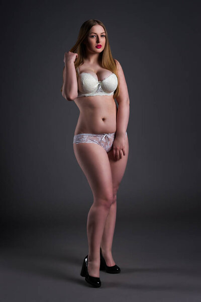Plus size sexy model in white underwear, fat woman on gray background, overweight female body