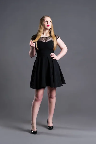 Plus grootte mannequin in zwarte jurk, dikke vrouw op grijze studio achtergrond, overgewicht vrouwelijk lichaam — Stockfoto