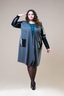 Artı boyutu moda modeli selamlıyor içinde rahat kıyafetler, bej studio arka planda, şişman kadın kilolu kadın bedeni
