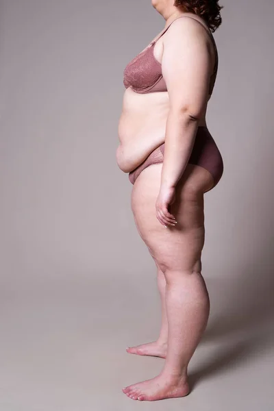 Dicke Frau in Unterwäsche, übergewichtiger weiblicher Körper auf grauem Hintergrund — Stockfoto