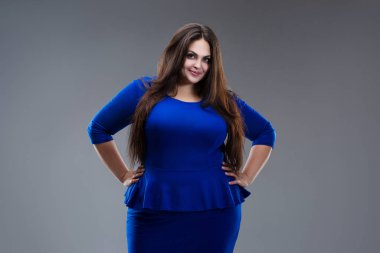 Mavi elbiseli mutlu artı beden modeli, gri arka planda uzun saçlı şişman kadın, vücut pozitifliği.