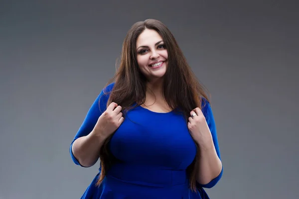 Happy plus size model in blue dress, fat woman with long hair on gray background, body positive concept — Stock Photo, Image