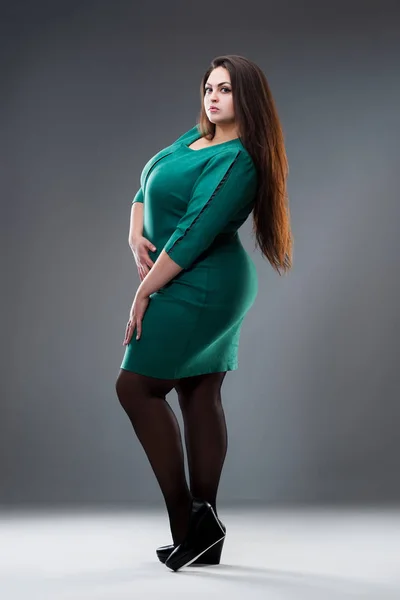 Plus size model in green dress, fat woman with long hair on gray background, body positive concept — Stock Photo, Image