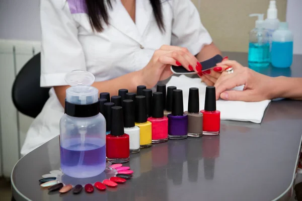 O mestre usa um arquivo de unhas, fazendo uma manicure no salão de spa — Fotografia de Stock