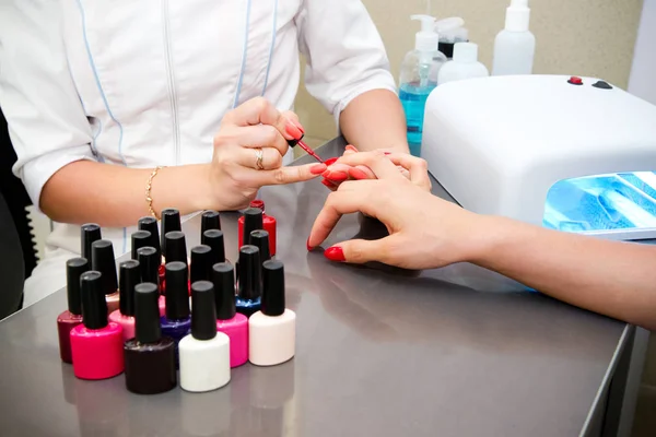 Master applies gel polish on nails in manicure salon — Stock Photo, Image