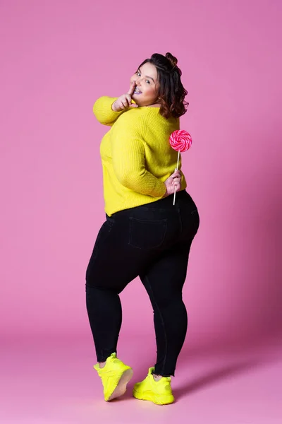 Além de modelo de tamanho em vestido azul com grande pirulito, mulher gorda no fundo rosa — Fotografia de Stock