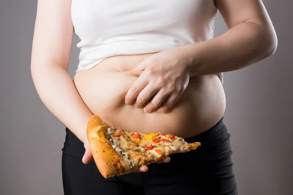 Жирная женщина с кусочком пиццы, концепция нездорового питания — стоковое фото