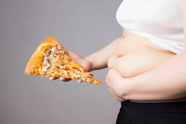 Fat woman with a piece of pizza, unhealthy nutrition concept