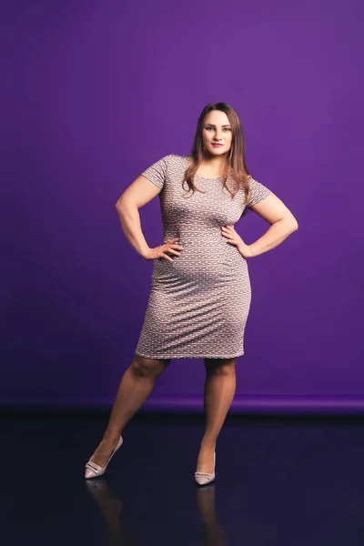 Модель plus size в платье midi, толстая женщина на фиолетовом фоне — стоковое фото