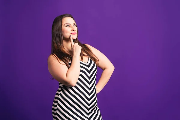 Pensive pize size model in striped dress, fat woman on purple background — 스톡 사진