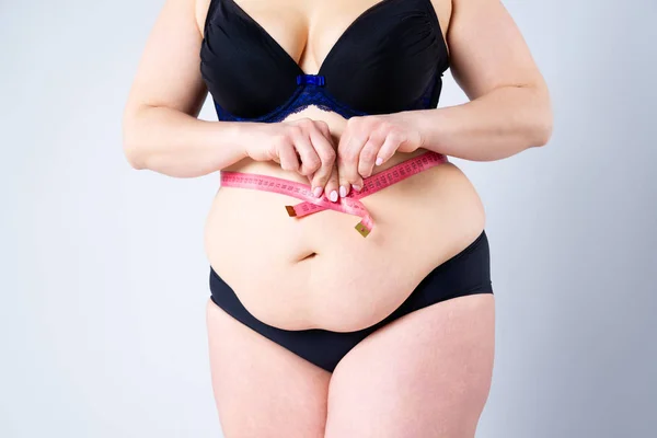 Толстая женщина с дряблым животом размером талии, избыточный вес женского тела на сером фоне — стоковое фото