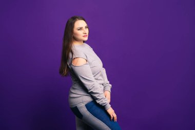 Artı günlük kıyafetlerle beden modeli, mor arka planda şişman kadın, vücut pozitifliği.