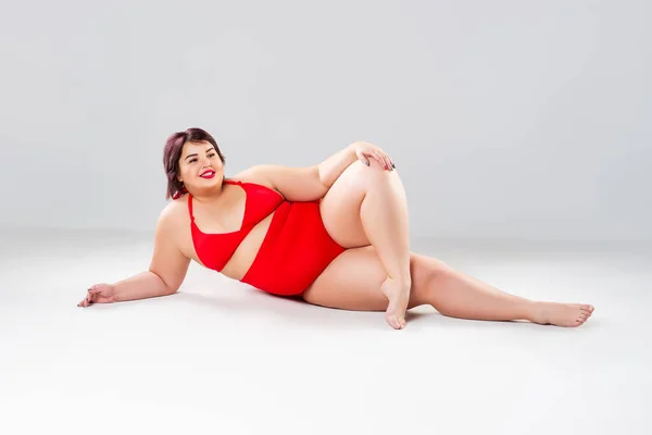 Artı Kırmızı Mayo Giyen Gri Arka Planda Çamaşırlı Şişman Kadın — Stok fotoğraf