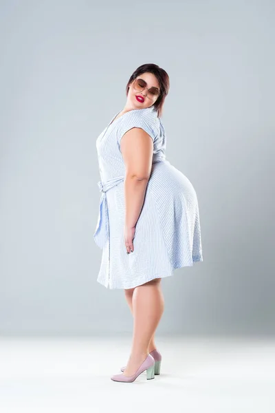 Young beautiful plus size model in black dres, xxl woman on gray studio  background Stock Photo by ©starast 143083977