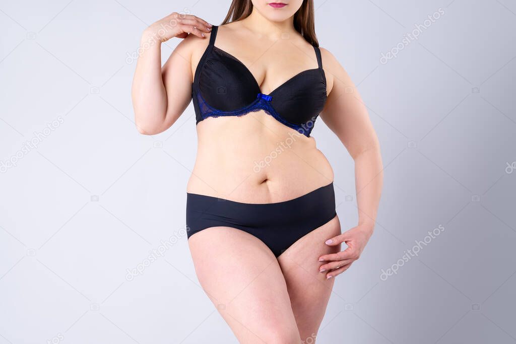Plus size model in black lingerie, fat woman on gray background, overweight female body, studio shot