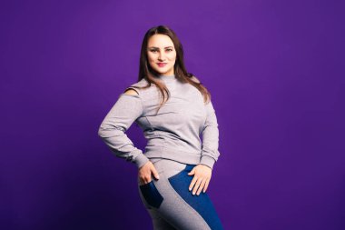 Artı spor giyim modeli, mor arka planda şişman kadın, vücut pozitifliği.