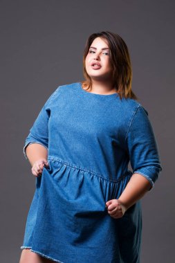 Artı kot elbiseli bir manken, gri arka planda şişman bir kadın, vücut pozitifliği