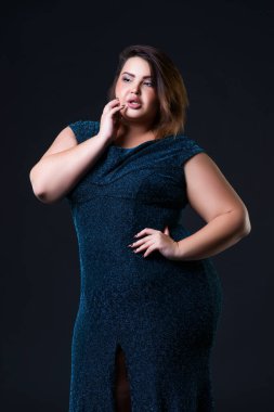 Artı yeşil gece elbisesi içinde manken boy, siyah arka planda şişman kadın, vücut pozitifliği.