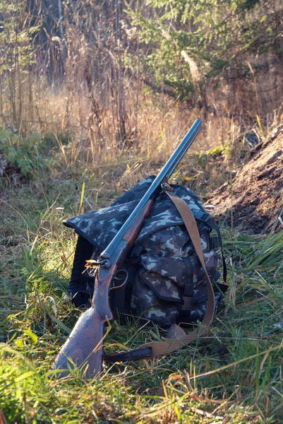 Hunting rifle and backpack in the woods — Stock Photo, Image