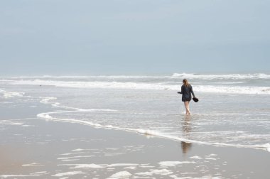 Dış Bankalar kıyı boyunca sörf yürüyen genç kadın