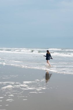 Dış Bankalar kıyı boyunca sörf yürüyen genç kadın
