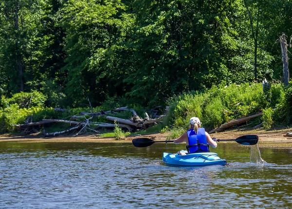lone female in a kayak on a river in the wilderness