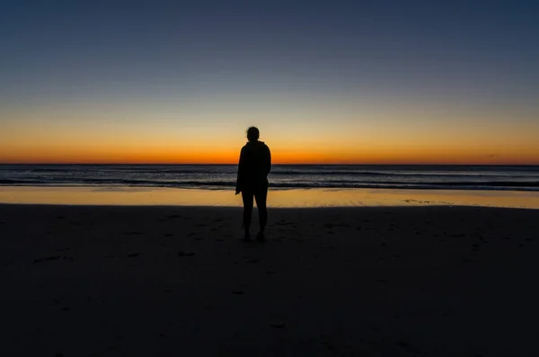 Junge Frau beobachtet den Sonnenaufgang über dem Ozean — Stockfoto