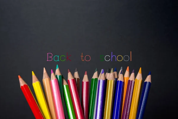 Lápices de colores sobre fondo de pizarra con texto "Volver a la escuela", concepto de vuelta a la escuela — Foto de Stock