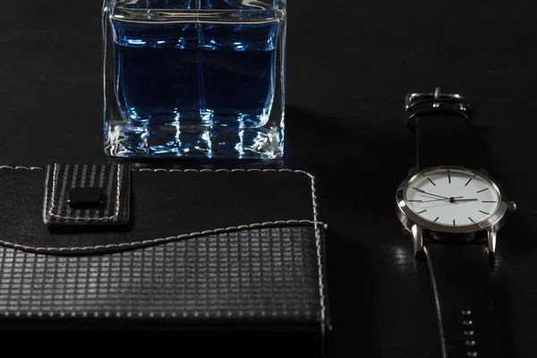 Man perfume, watch, notebook on a black background