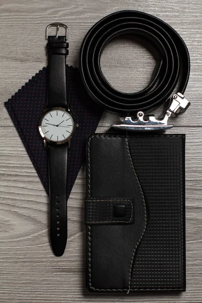 Leather belt, watch, silk handkerchief, notebook on a gray woode