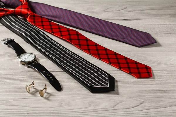 Corbatas de seda de color, reloj de pulsera, gemelos en un bac de madera gris — Foto de Stock