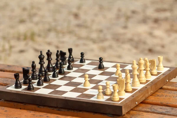 Chess board with chess pieces on wooden bench. Outdoors chess ga