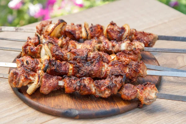 Gegrild varkensvlees op een spies gebakken op de grill op houten hakken — Stockfoto