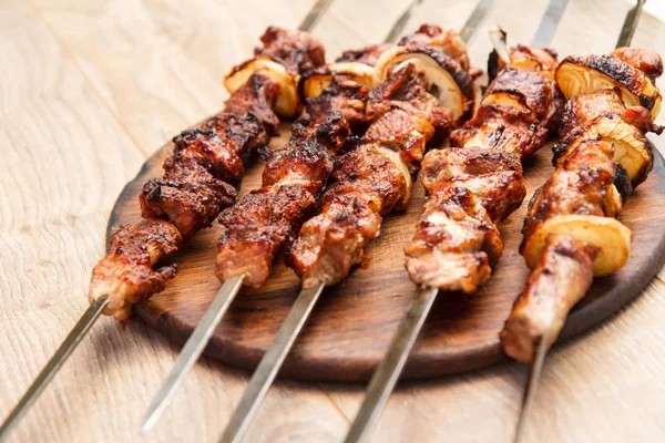 Gegrild varkensvlees op een spies gebakken op de grill op houten hakken — Stockfoto