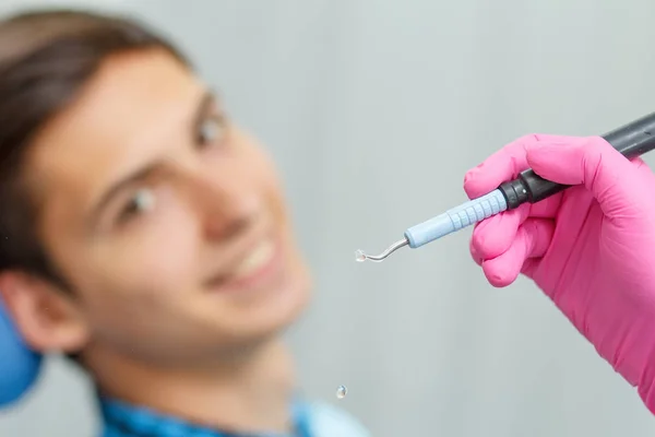 Pembe eldiven giymiş doktor ultrasonik diş ölçekleyici w tutuyor
