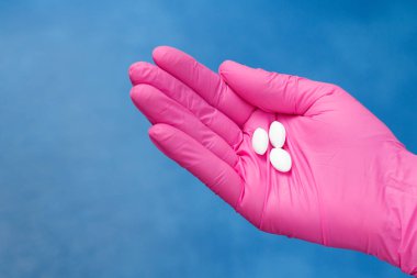 Bir kadın doktor beyaz hap yığını ile pembe eldiven eller