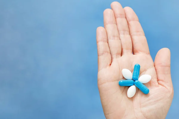 Primer plano de la mano sosteniendo píldoras azules y blancas en la forma l — Foto de Stock