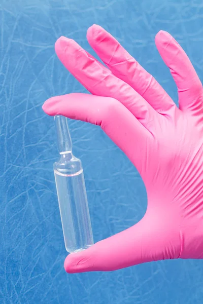Mano de doctora en guante rosa con ampolla y medicina — Foto de Stock
