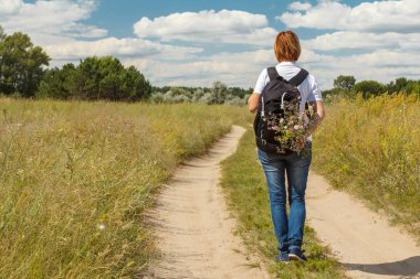 Uzun yürüyüşe çıkan kimse kırsal yolda yürürken sırt çantası ile