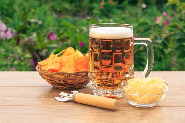 Tasse en verre de bière sur table en bois avec croustilles en osier ba — Photo