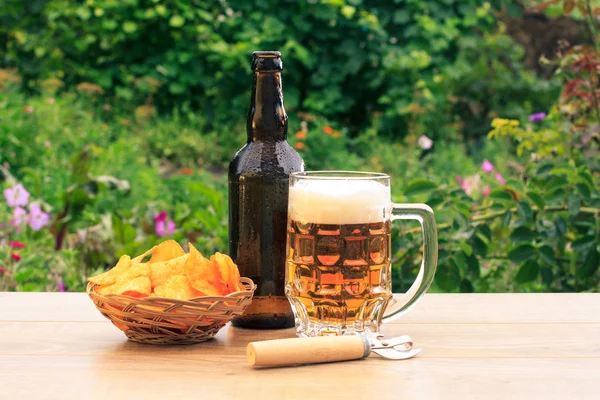 Tasse en verre de bière et bouteille de bière sur table en bois avec pomme de terre — Photo