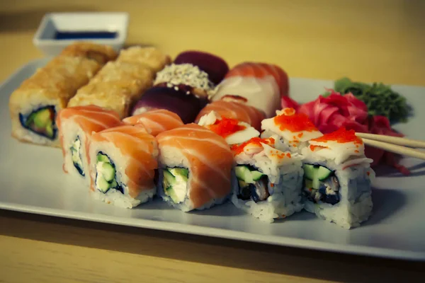 Verschillende sushi rolt met sojasaus op houten bureau — Stockfoto