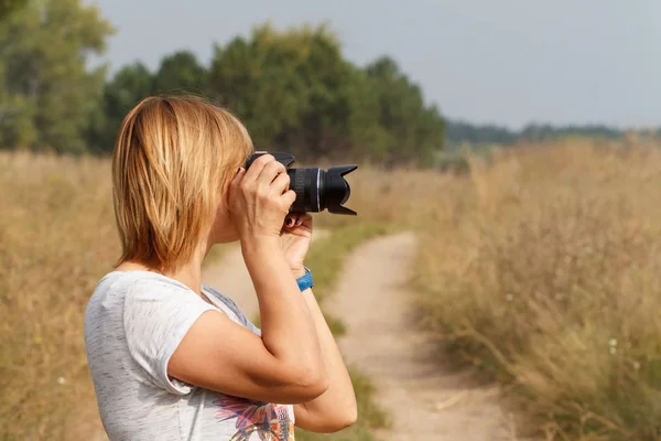 Νεαρή γυναίκα κρατώντας ψηφιακή φωτογραφική μηχανή και λήψη φωτογραφιών — Φωτογραφία Αρχείου
