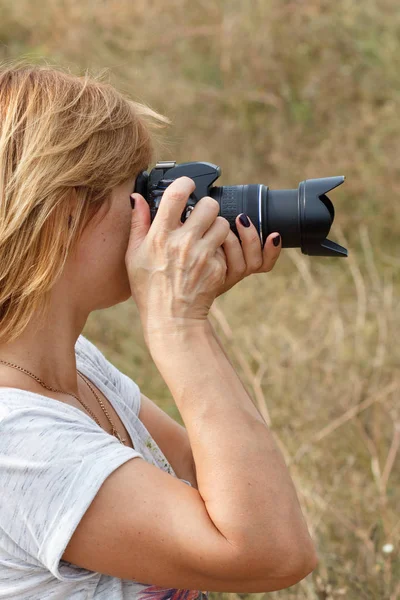 Молодая женщина держит цифровую камеру и фотографирует — стоковое фото
