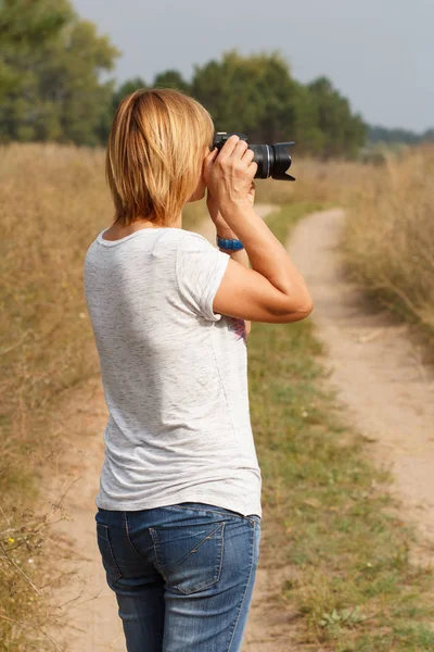 Jeune femme tenant un appareil photo numérique et prenant des photos — Photo